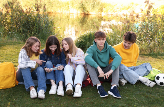 A group of five young adults sitting on the grass