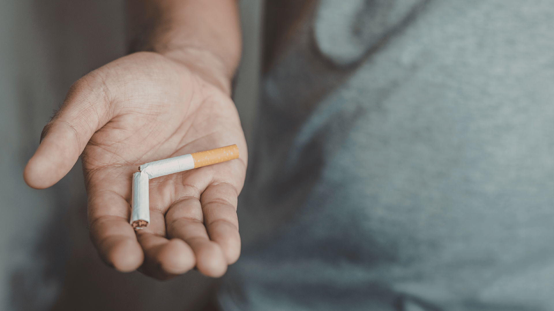 A person holding a snapped cigarette in their palm