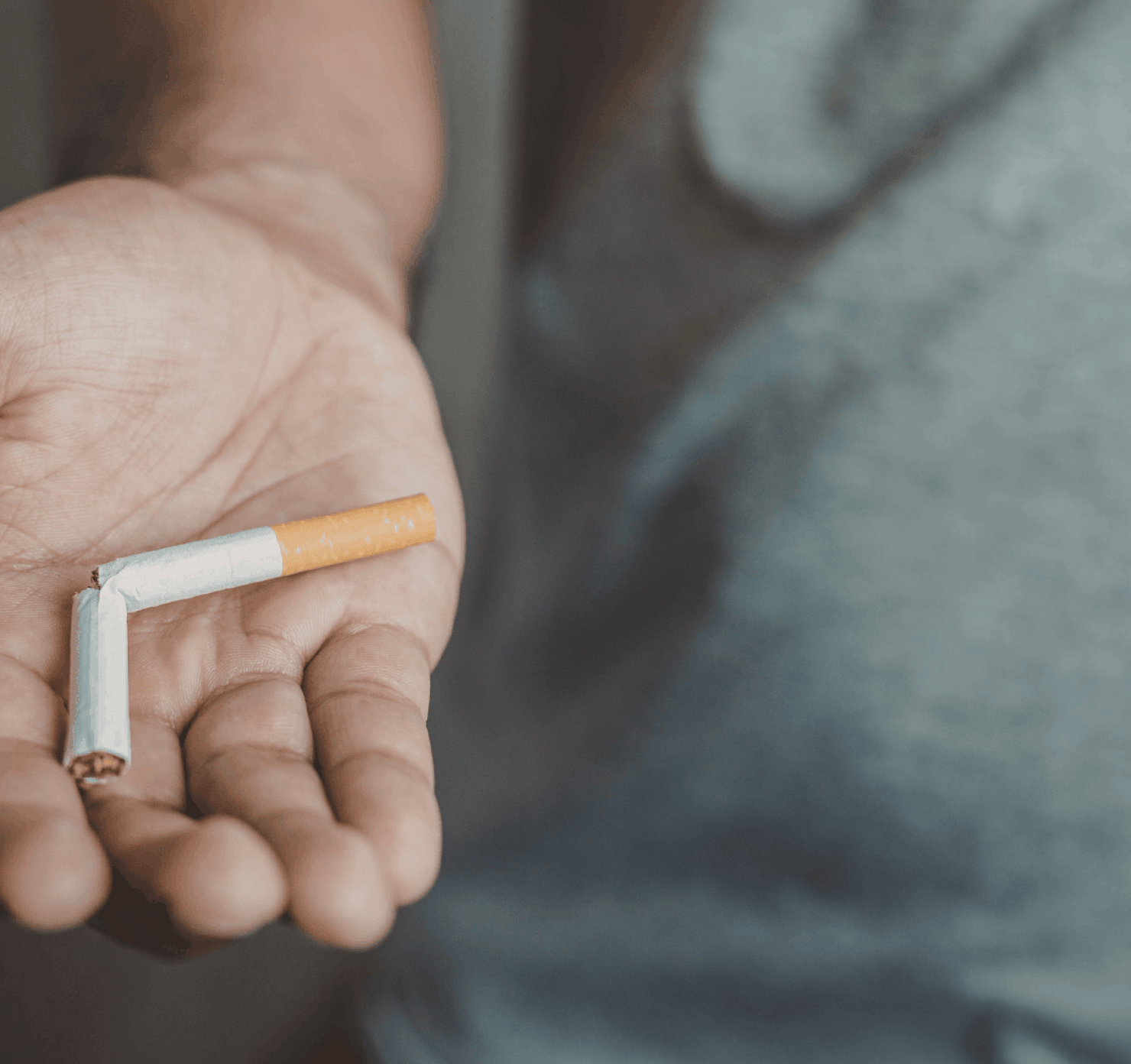 A person holding a snapped cigarette in their palm