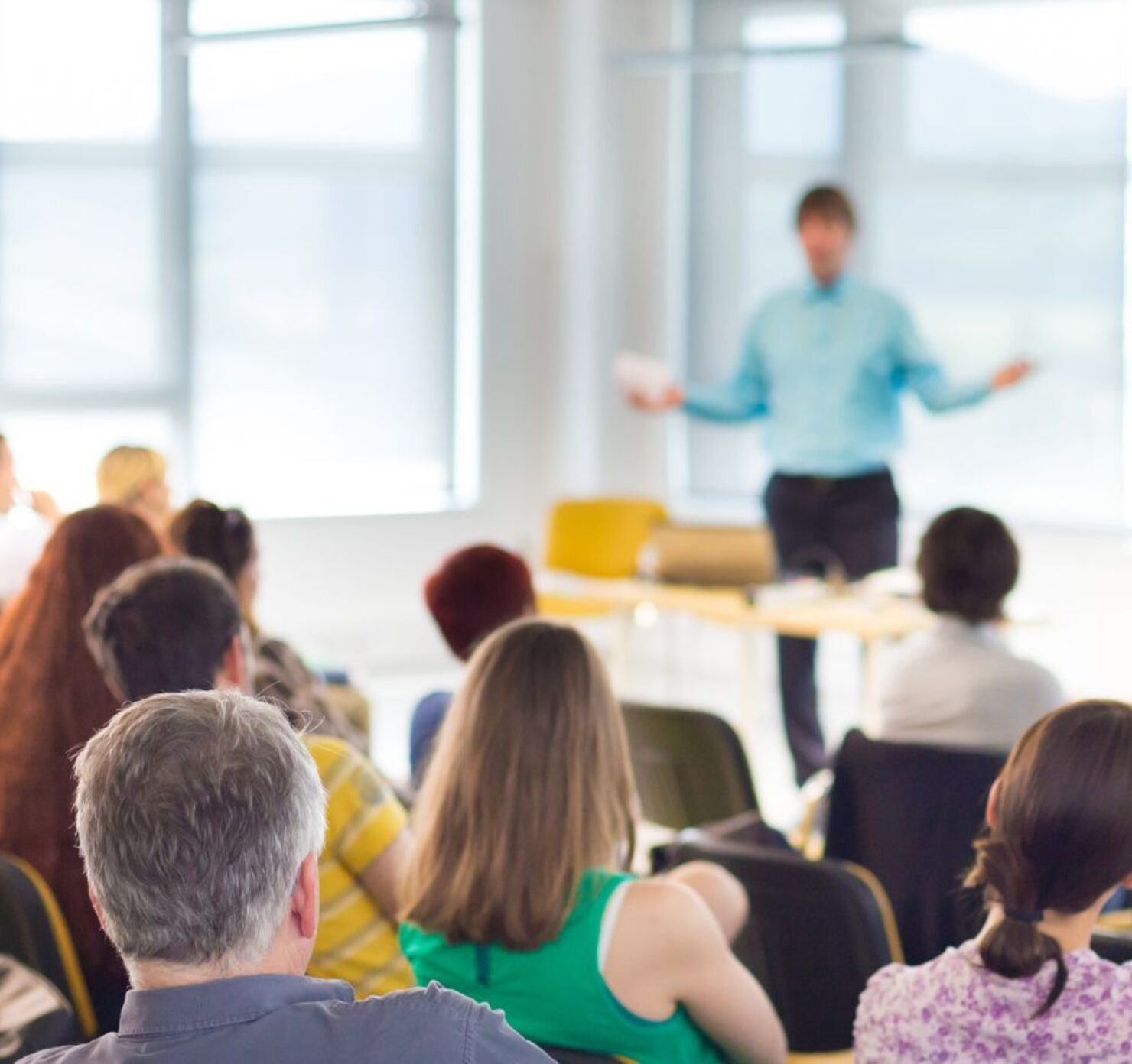 Seated people watch a speaker in a conference room