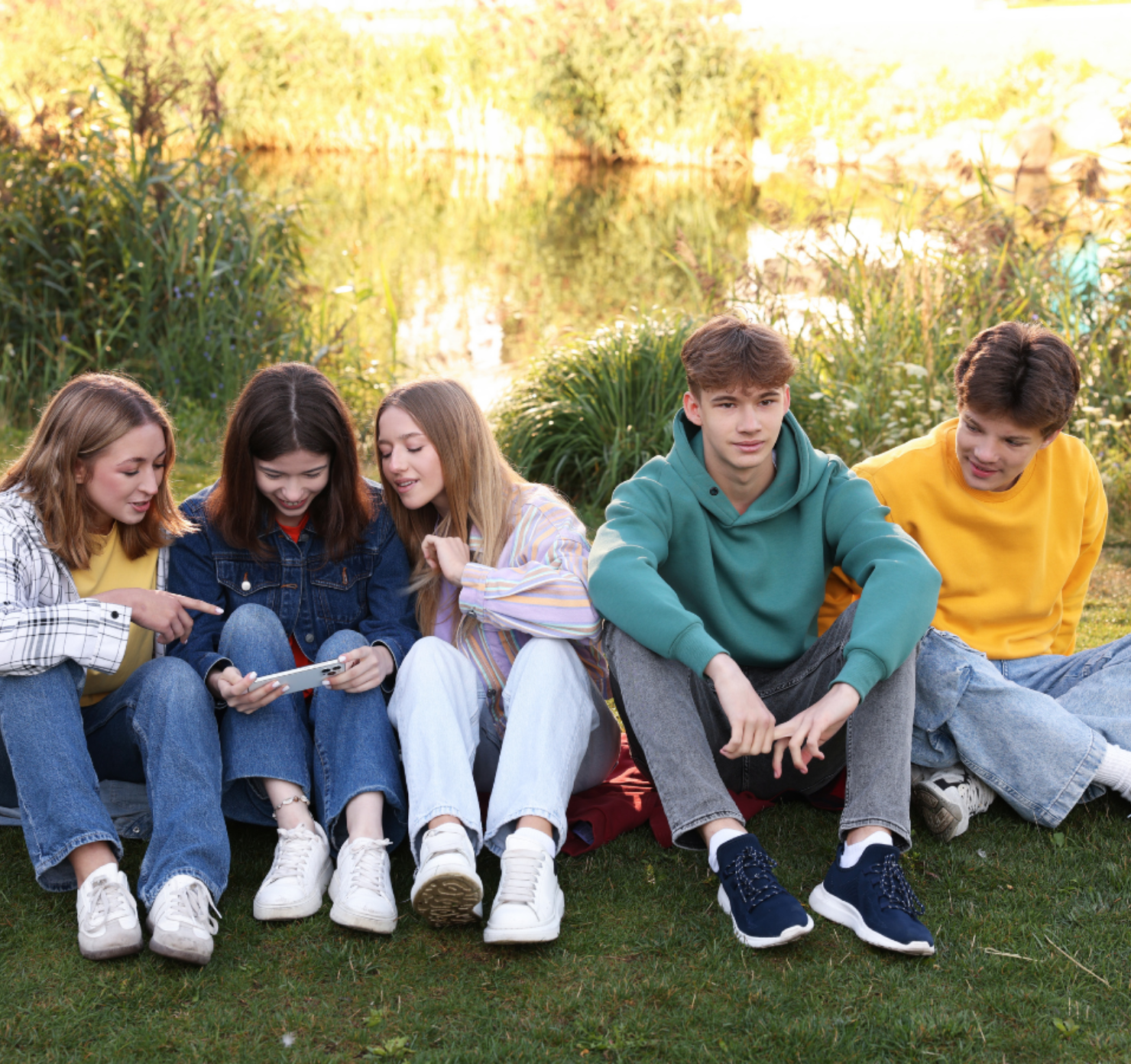 A group of five young adults sitting on the grass