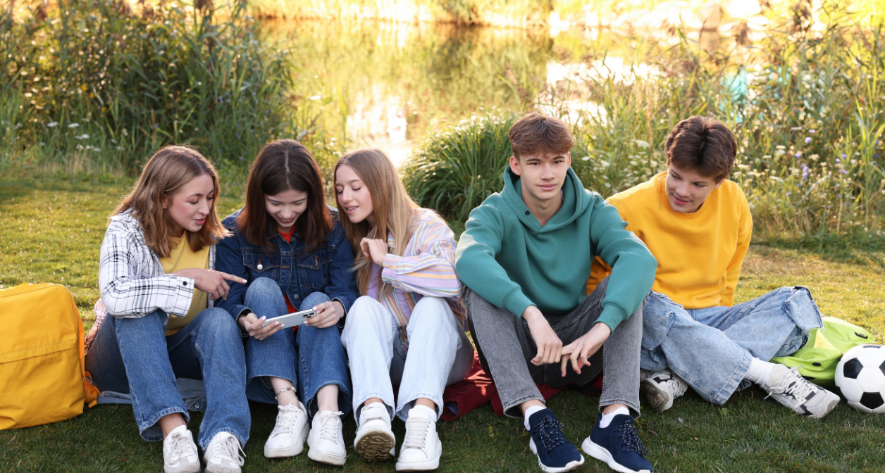 A group of five young adults sitting on the grass